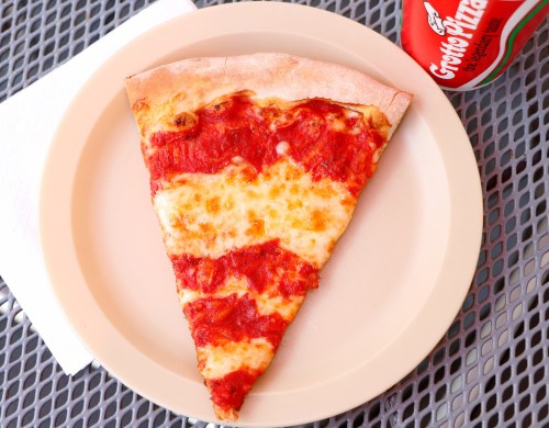 A slice of cheese pizza with tomato sauce on a plate, next to a can of soda on a table.