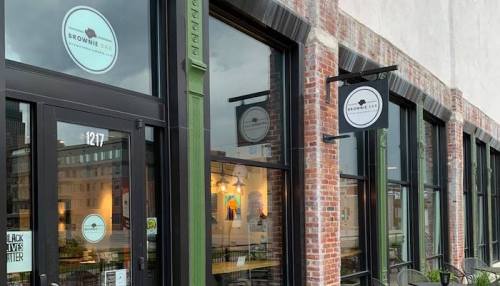 Exterior of Brownie Bar, featuring large windows, a sign, and a welcoming entrance in a brick building.