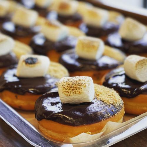 A tray of donuts topped with chocolate frosting, graham cracker crumbs, and toasted marshmallows.