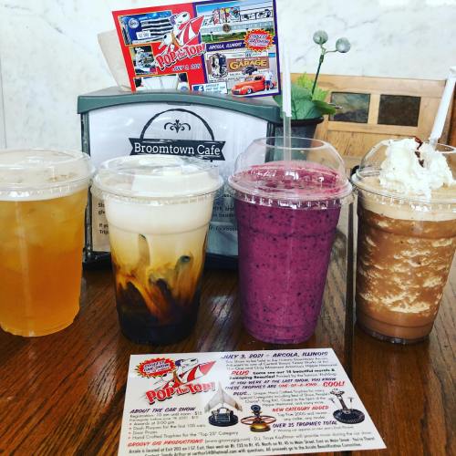 Four colorful drinks in clear cups sit on a table, alongside a menu at Broomtown Cafe.