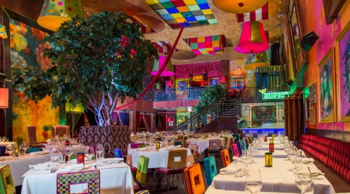 Vibrant restaurant interior with colorful decor, tables set for dining, and a large tree centerpiece.