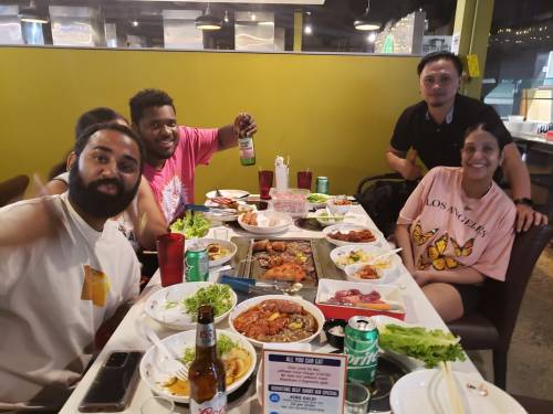 A group of friends enjoying a feast at a restaurant, surrounded by various dishes and drinks on the table.
