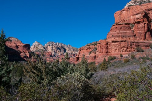 A scenic view of red rock formations and green vegetation under a clear blue sky.