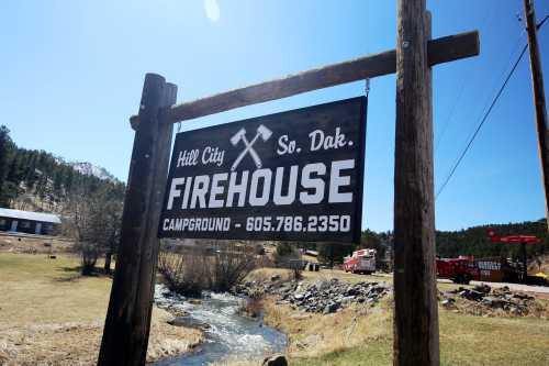 Sign for Hill City Firehouse Campground in South Dakota, featuring a scenic view with a stream and trees.