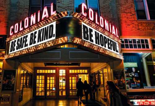 The Colonial Theater marquee displays "Be Safe. Be Kind. Be Hopeful" with a vibrant, illuminated entrance.