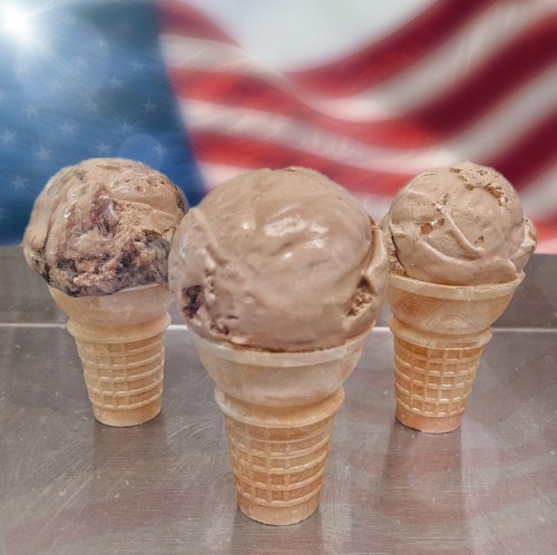 Three chocolate ice cream cones in front of a blurred American flag background.