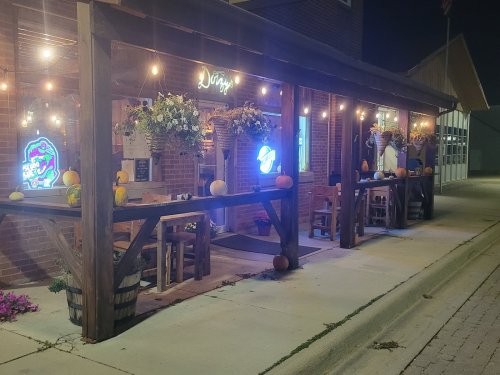 A cozy outdoor dining area at night, decorated with pumpkins and string lights, creating a warm atmosphere.