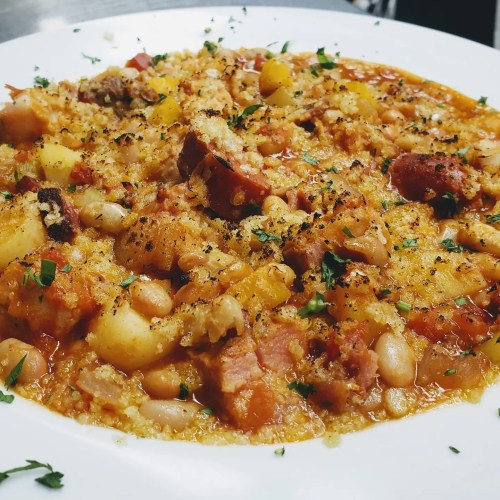 A hearty dish featuring beans, potatoes, and spices, topped with a sprinkle of herbs and a golden crust.