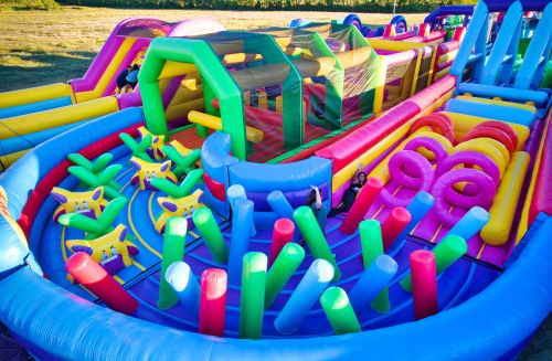 A colorful inflatable water park with slides, obstacles, and play areas for children on a sunny day.