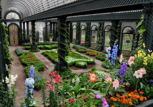 A lush garden with colorful flowers arranged in patterns, surrounded by ornate latticework and greenery.