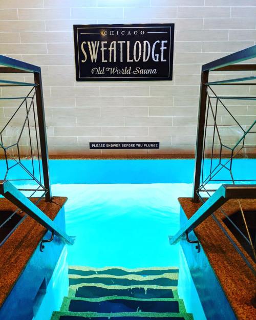 A staircase leading down to a turquoise pool, with a sign reading "Chicago Sweat Lodge Old World Sauna."
