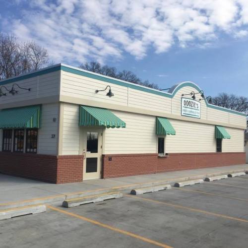 A single-story building with a light-colored exterior and green awnings, featuring a welcoming entrance and clear blue sky.