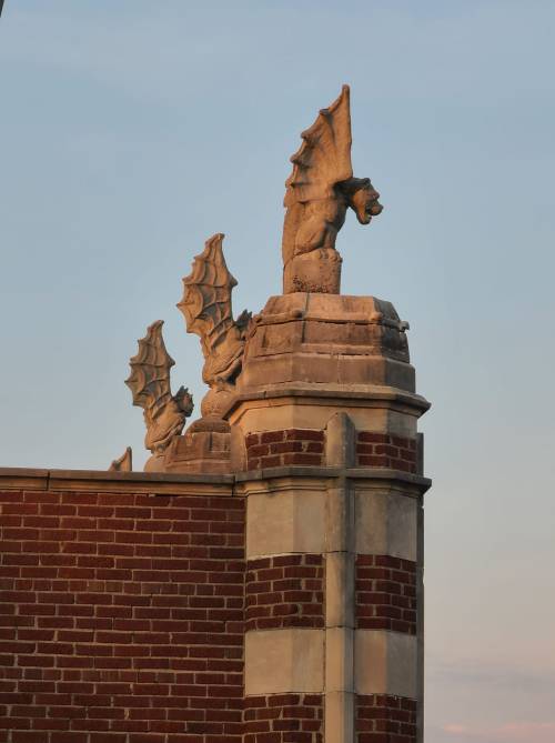 Gargoyle sculptures perched on a brick building, with a clear sky in the background.