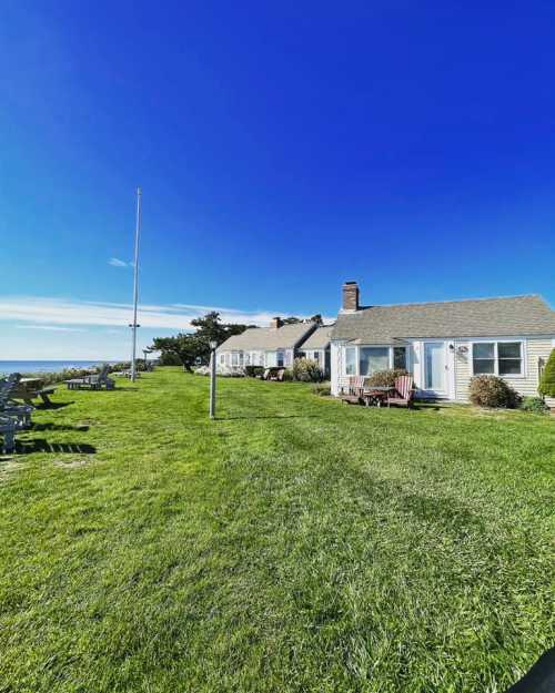 A sunny coastal scene featuring a grassy area with cottages and a clear blue sky.