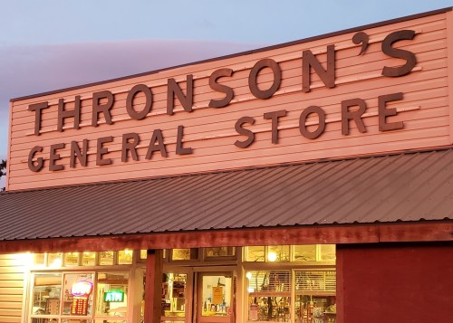 Sign for Thronson's General Store at dusk, featuring large letters and illuminated windows.