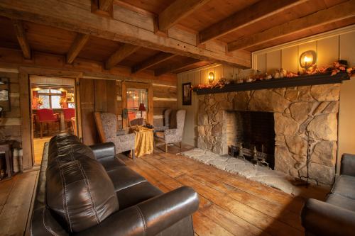 Cozy rustic living room with wooden beams, a stone fireplace, and comfortable seating. Warm, inviting atmosphere.