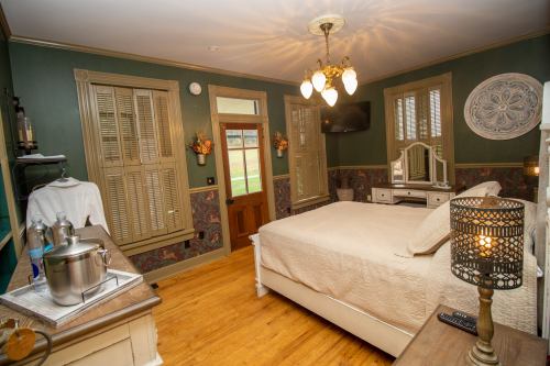 Cozy bedroom with a large bed, wooden furniture, and green walls, featuring a door and window with natural light.