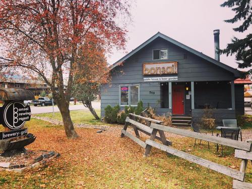A cozy gray house with a sign for Bonsai Brewing Project, surrounded by autumn trees and a wooden fence.