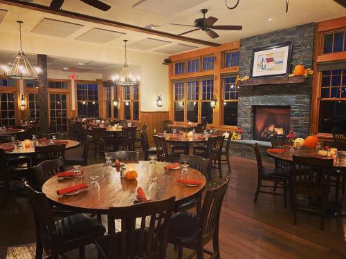 Cozy restaurant interior with wooden tables, chairs, and a stone fireplace, decorated for fall with pumpkins.