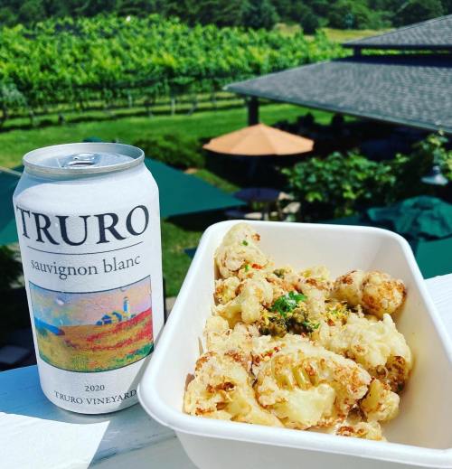 A can of Truro Sauvignon Blanc next to a bowl of fried cauliflower, with a vineyard backdrop.