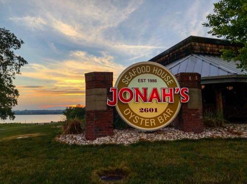 Sign for Jonah's Seafood House and Oyster Bar, with a sunset and water in the background. Established 1986.
