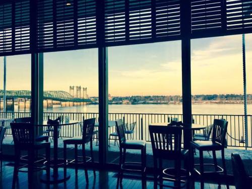 View from a restaurant with empty chairs, showcasing a river and a bridge through large windows.