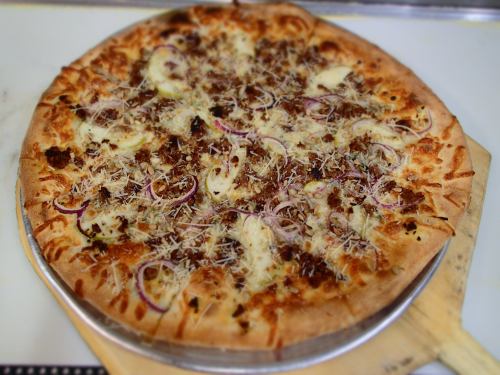 A freshly baked pizza topped with cheese, onions, and savory meat, resting on a wooden pizza peel.