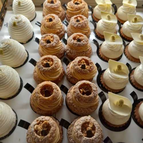 A display of assorted pastries, including cream-filled and topped desserts in various colors and textures.