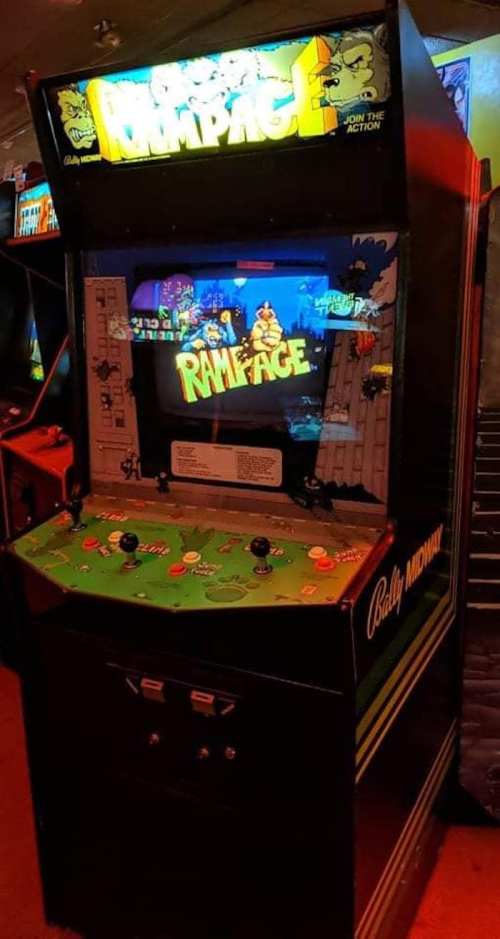 An arcade cabinet for the game "Rampage," featuring colorful graphics and a joystick control panel.