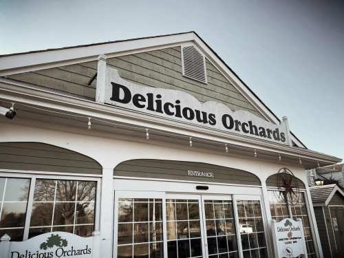 Signage of Delicious Orchards on a building exterior, featuring large letters and a welcoming entrance.