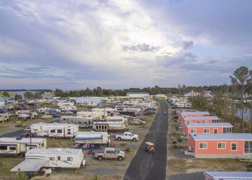 Aerial view of a large RV park with numerous trailers and colorful cabins under a cloudy sky.