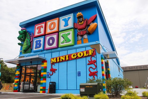 Colorful building with "Toy Box" and "Mini Golf" signs, featuring large toy figures on the facade.