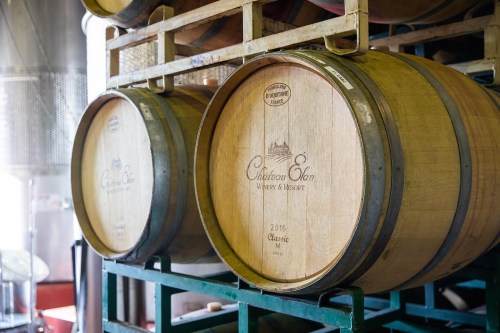 Two wooden wine barrels stacked on a rack in a winery, labeled with "Château Elan" and "2016 Classic."