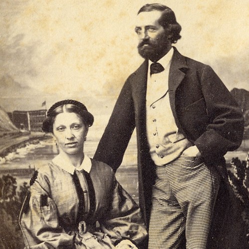 A vintage portrait of a man and woman, both dressed in 19th-century attire, with a coastal background.