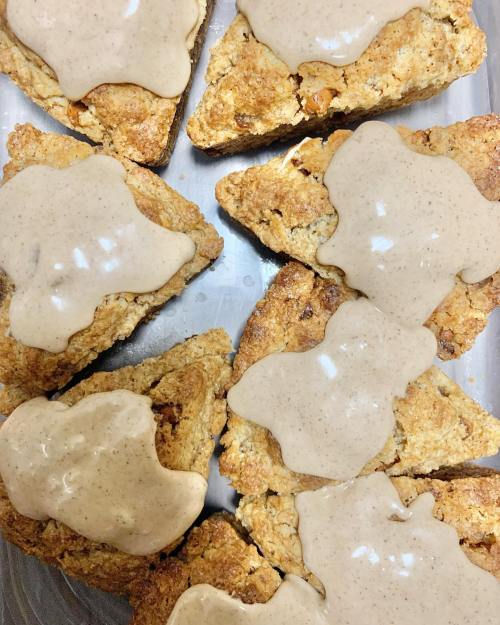 A tray of freshly baked scones topped with a creamy glaze, featuring a mix of nuts and a golden-brown crust.