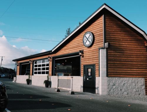 A wooden building with a sign featuring a railroad logo, set against a clear blue sky.