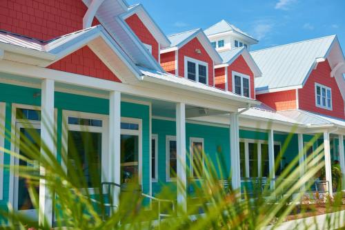 Colorful coastal-style houses with vibrant red, orange, and turquoise siding under a clear blue sky.