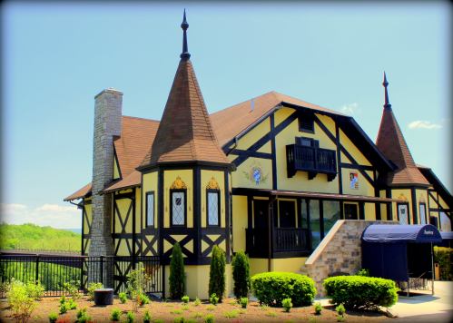 A charming yellow and black Tudor-style building with pointed roofs and decorative features, surrounded by greenery.