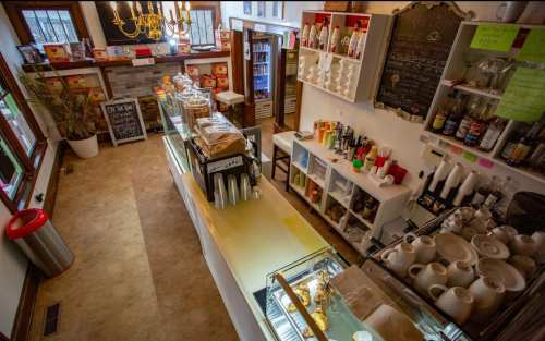 A cozy café interior featuring a counter with drinks, pastries, and decorative shelves in a warm, inviting atmosphere.