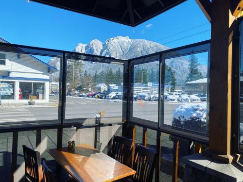 View from a cozy restaurant with a wooden table, showcasing mountains and a clear blue sky outside.
