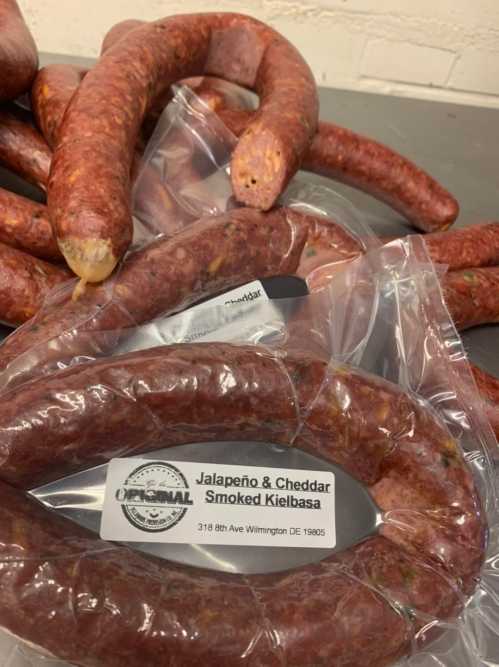 Several packages of Jalapeño and Cheddar Smoked Kielbasa sausages, some partially unwrapped, on a surface.