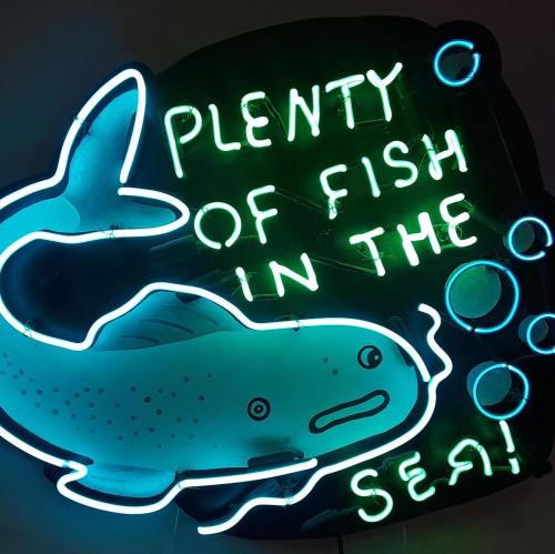 Neon sign featuring a fish and the phrase "Plenty of fish in the sea!" with bubbles around it.