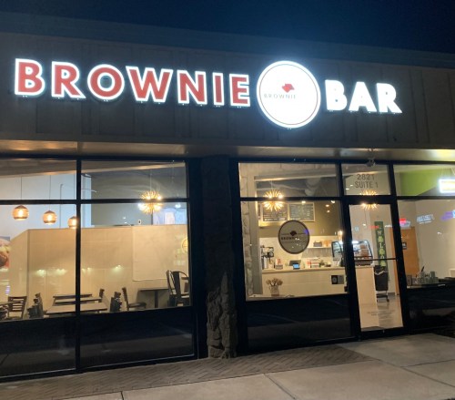 Exterior of Brownie Bar, featuring illuminated signage and large windows showcasing a cozy interior.