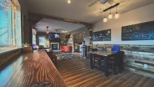 Cozy living space with wooden accents, a dining area, and a fireplace, featuring warm lighting and colorful artwork.