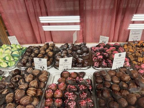 A display of assorted chocolate truffles and candies in various colors and designs, neatly arranged in trays.