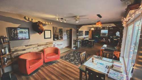 Cozy café interior with wooden accents, red chairs, a moose head on the wall, and a warm, inviting atmosphere.