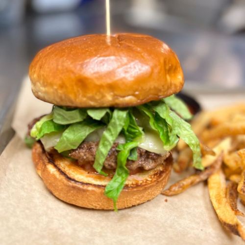 A juicy burger with lettuce and cheese on a toasted bun, served with crispy fries on the side.