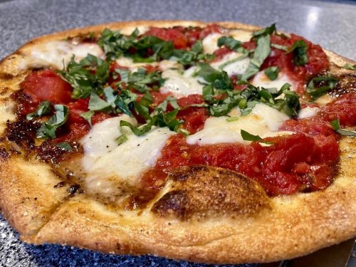 A freshly baked pizza topped with mozzarella, tomato sauce, and fresh basil on a golden crust.