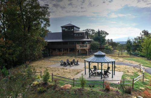 A spacious house with a gazebo and seating area, surrounded by trees and open land under a cloudy sky.