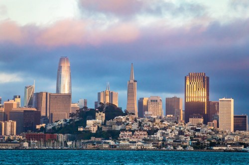 A skyline view of San Francisco with modern skyscrapers and a cloudy sky above.